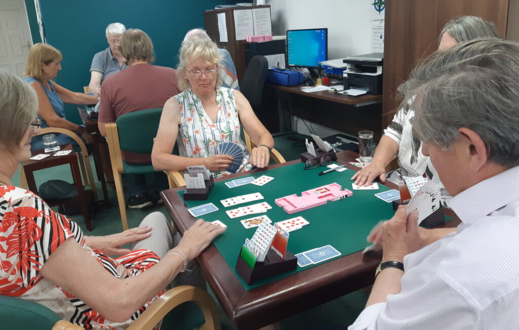 Quiet concentration of four people sitting at a table playing Bridge.