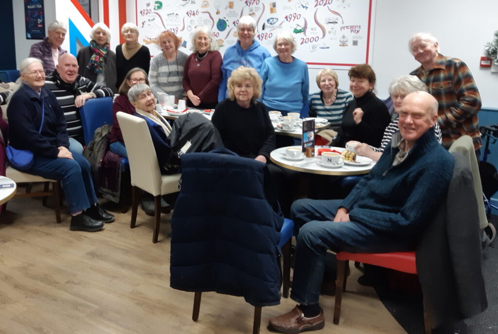 About 22 members of MOTO in the NAAFI cafe enjoying cake and a chat.
