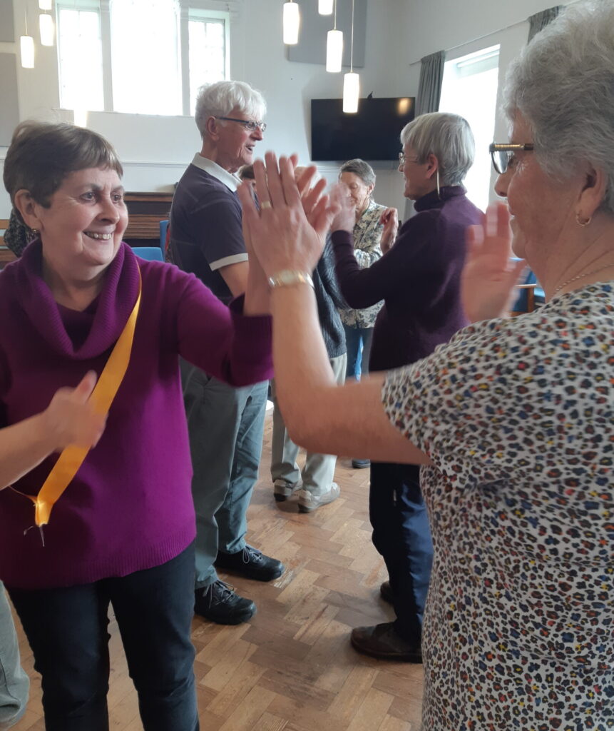 Ladies and gentlemen are dancing and smiling cheerfully.