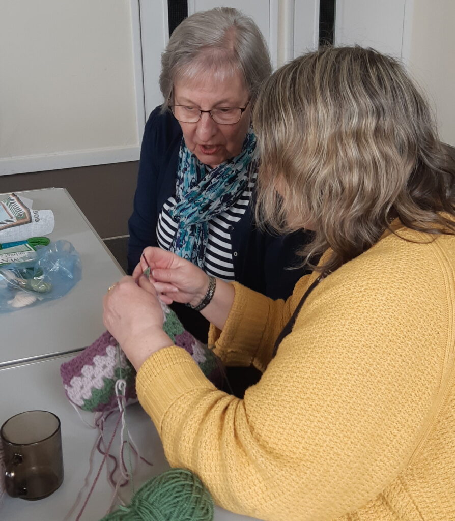 Two members of the group discussing a piece of crochet work.