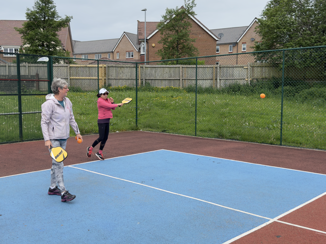 Two ladies playing Pickleball, one hitting a forehand.