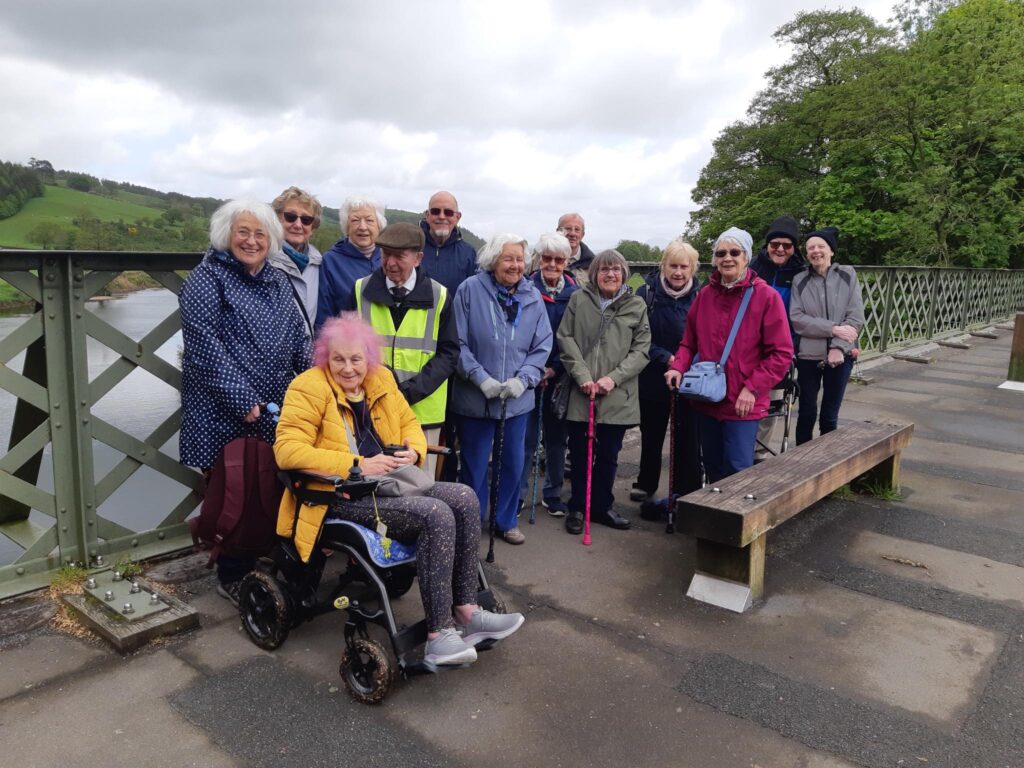 A group of Amlbers who have walked to the Crook o Lune, standing on the bridge with the river in the background.