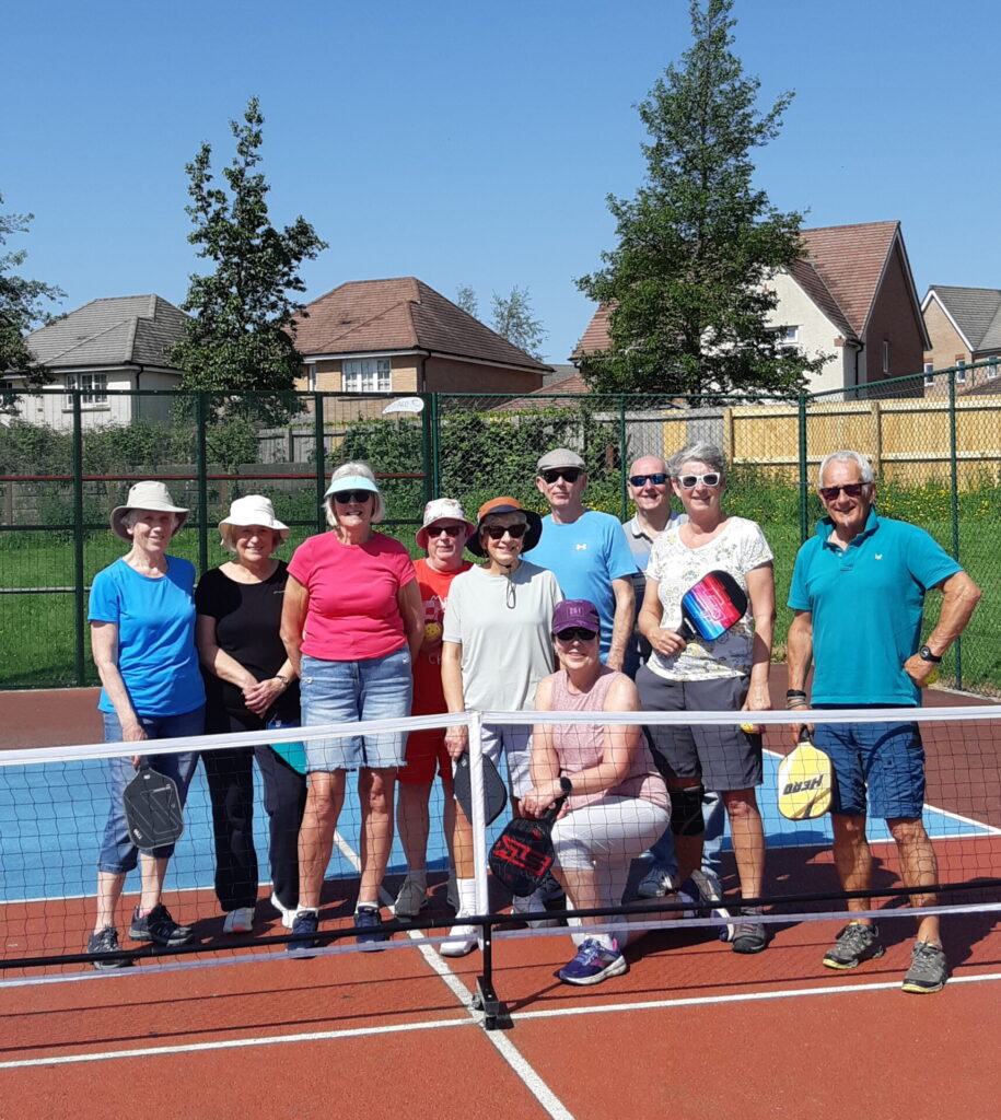 A group of Pickleballers in the sun wearing hats and sunglasses.