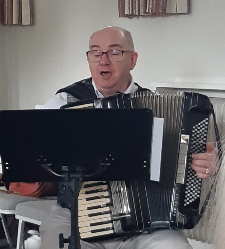 The leader playing the accordion and singing Mack the